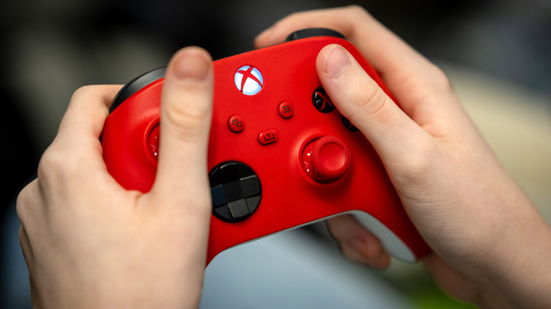 A close-up of someone holding a red Xbox Wireless Controller