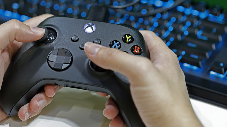 A close-up of someone holding a black Xbox Wireless Controller