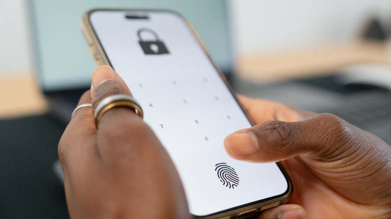 Person holding a phone showing a lock screen using PIN and fingerprint scanning