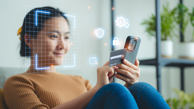 Person using their phone's facial recognition feature while holding a credit card