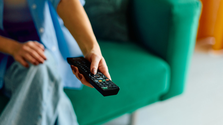 Person on couch using TV remote control