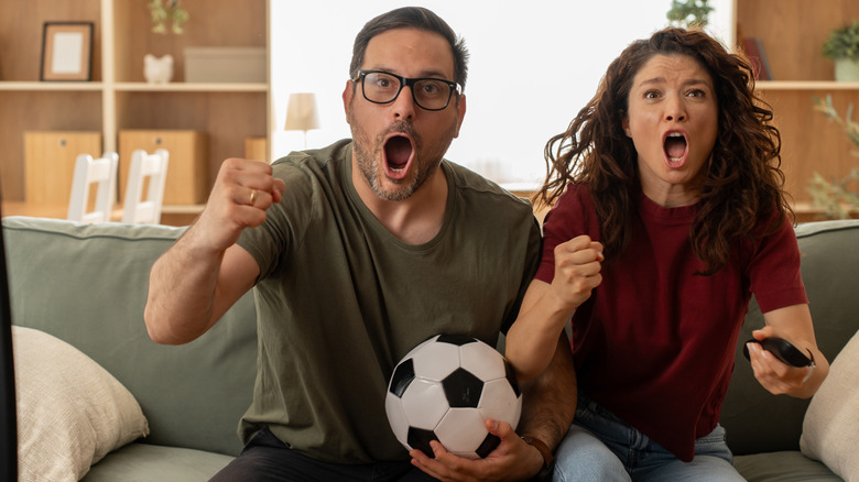 Couple on couch excitedly watching sports on TV