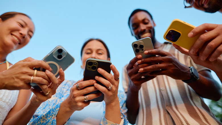 a group of people holding phones in various different cases and colors