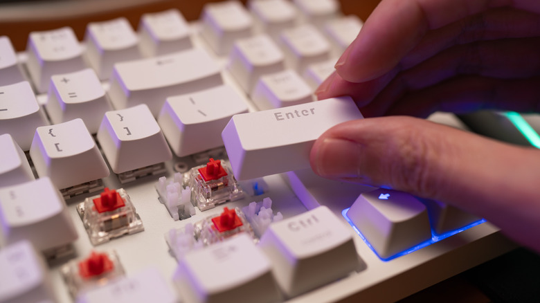 Hand holding keycap above switch and plate mount stabilizer