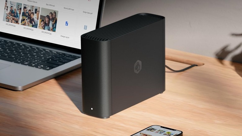 The Synology BeeStation NAS set up on a desk, next to a laptop and smartphone.