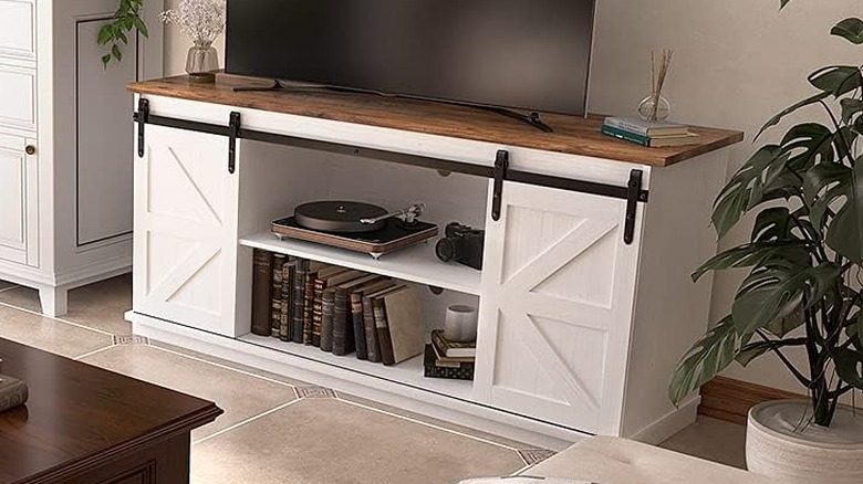 The Jummico furniture set up in a living room. A TV sits on top of the stand, and the barn doors reveal the center storage-area, which has a record player and several books in it.