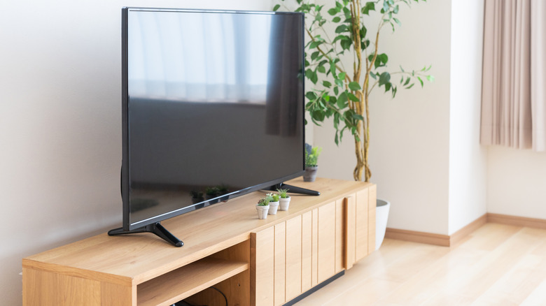 A TV sits on top of a TV stand in a modern apartment living room.