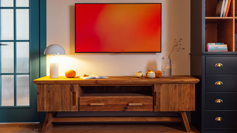 A wall-mounted TV with a red screen is centered over a TV stand in a modern living room.