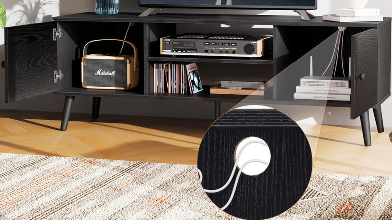 The Sweetcrispy Entertainment Center with Storage in a living room setting. A TV sits on top of it, and numerous AV components and accessories are underneath.