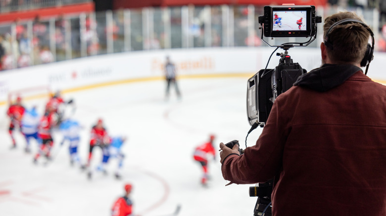 A camera man shooting a hockey game from the press box