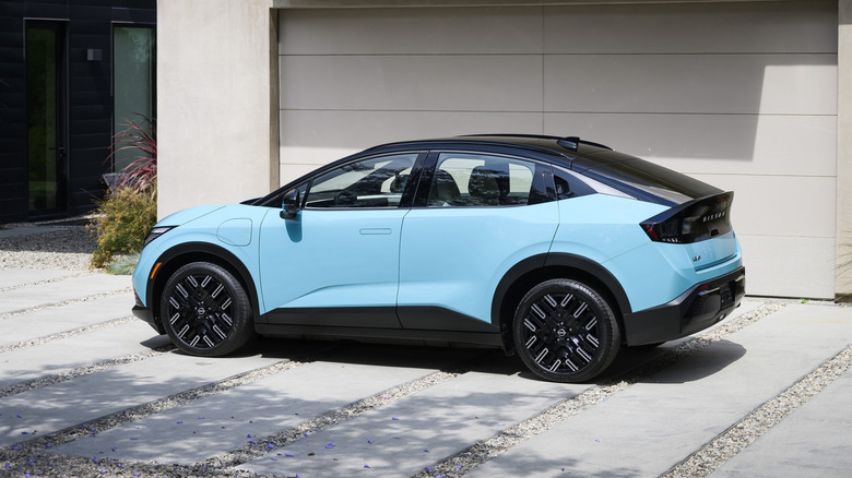 Blue Nissan Leaf car parked in front of house.