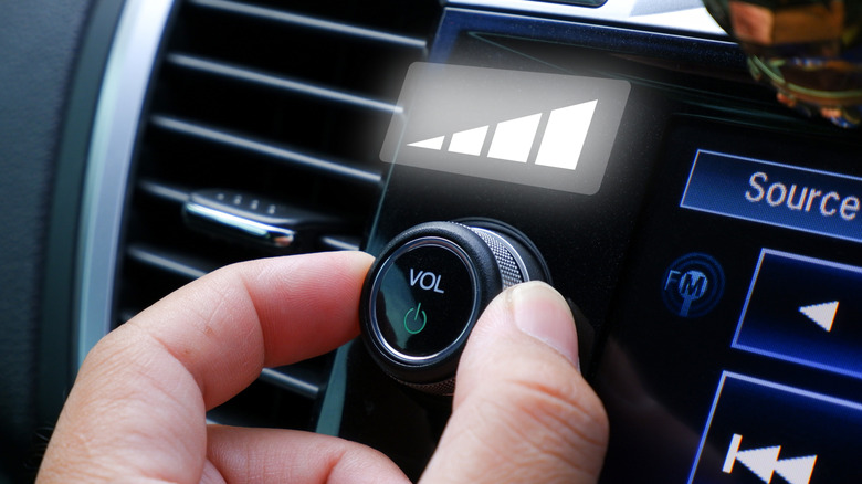A hand adjusting the volume knob on a vehicle's radio, with a render of volume levels above the knob