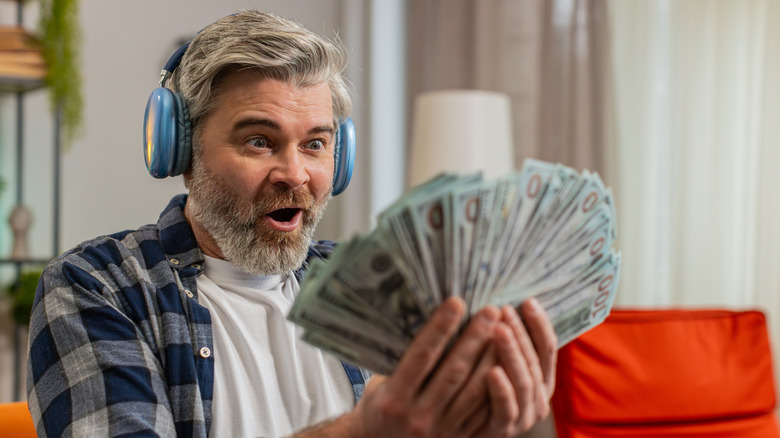 Man wearing headphones holding lots of money