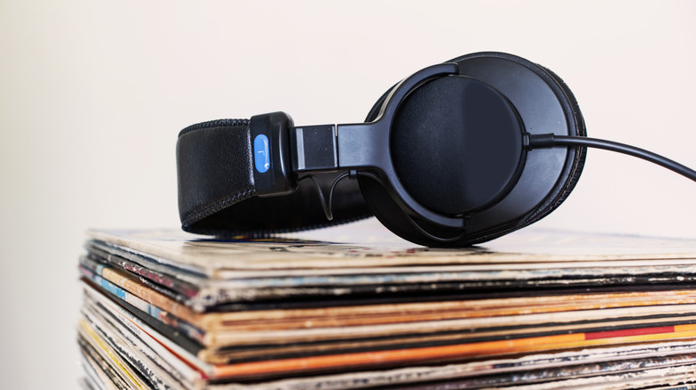 Headphones sitting on top on a stack of vinyl records