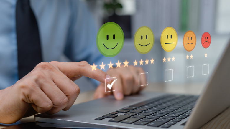 Person working on a laptop with smiling faces indicating a satisfaction survey.