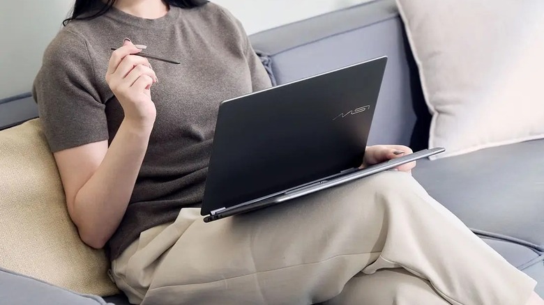 A close-up of a person using the MSI Prestige 14 Flip AI+ in their lap with a stylus in hand