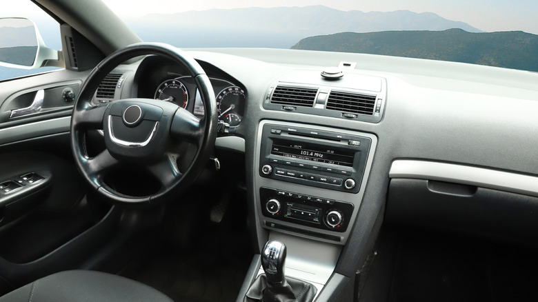The interior of a vehicle, with hills visible from the windscreen