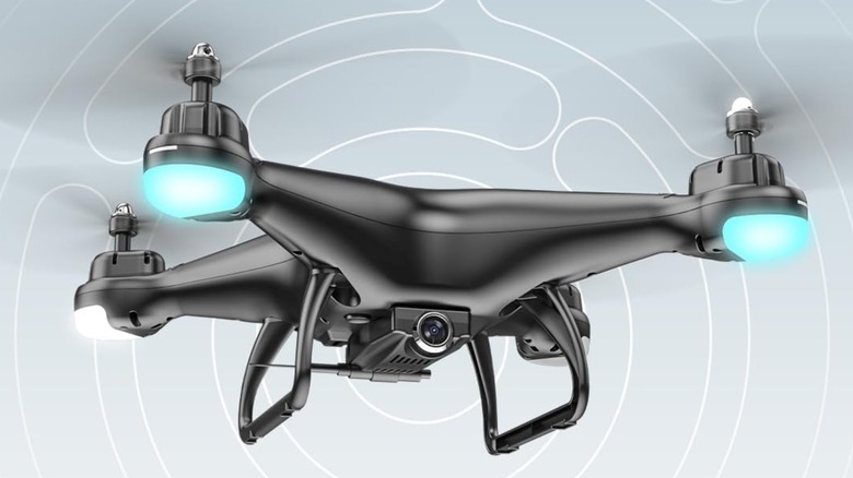 A Holy Stone HS110D is flying in the air against a background that features thin, circular lines