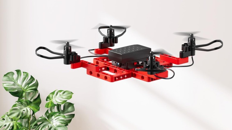 A red Techvio Mini Drone hovers against a white wall