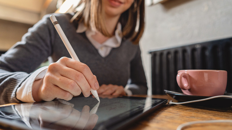 Person writing on a tablet using a stylus pen