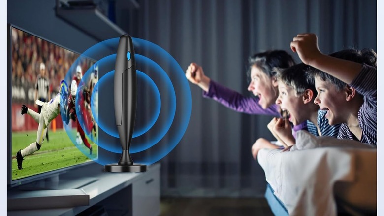 The QTBVAE Indoor Antenna placed on a TV stand in front of a TV. A family watches a sporting event and cheers.