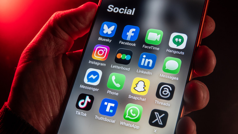 Various social apps on an iPhone held in hand.