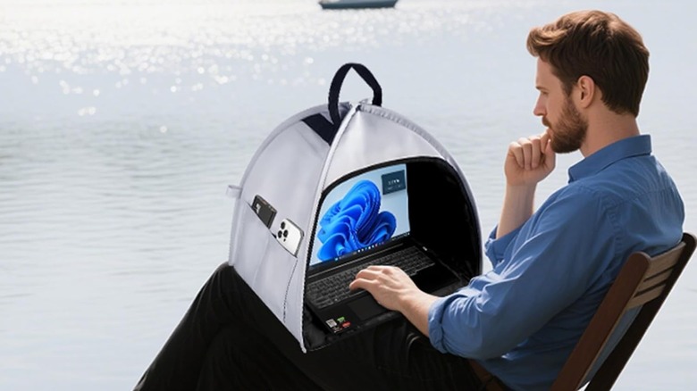A man using the Hoyixi Laptop Shade by a lake.