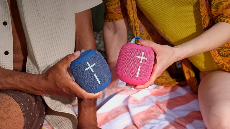 Two people holding Wonderboom 4 speakers, one blue and one pink.