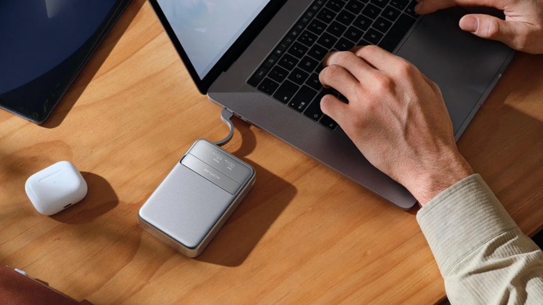 A man using a MacBook while an EcoFlow power bank charges it