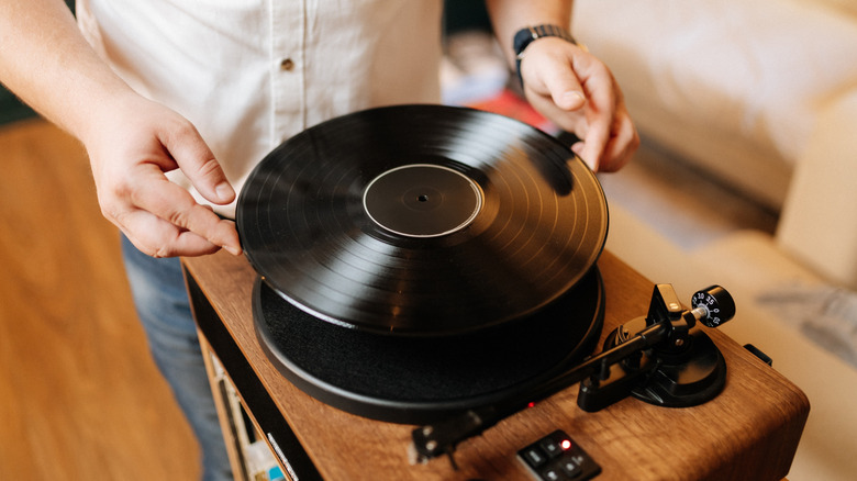 An individual holding a vinyl record in both hands, readying to position it atop a turntable