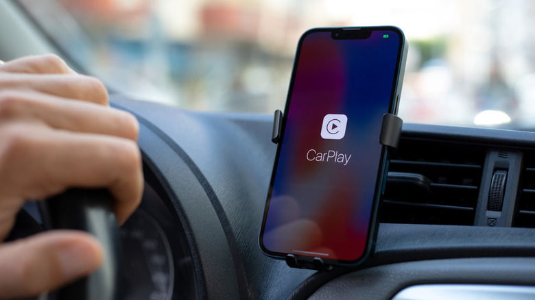A phone in a car vent holder showing the CarPlay loading screen