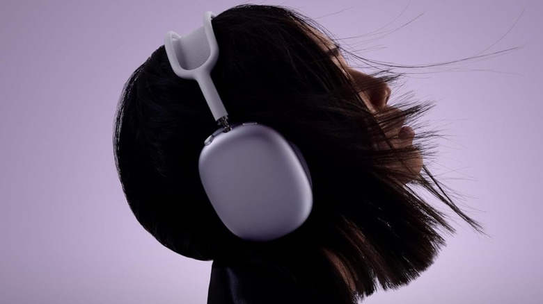 A side profile of a woman wearing a white set of AirPods Max