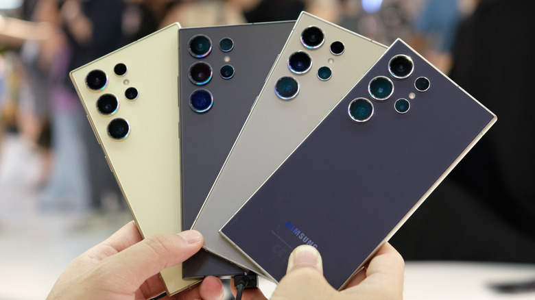 A person holding several Samsung Gaalaxy S24 Ultra smartphones