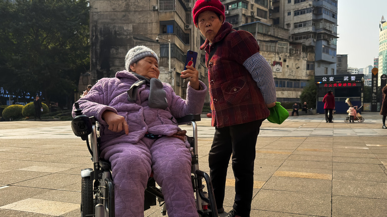 an elder person in a wheelchair using a smartphone