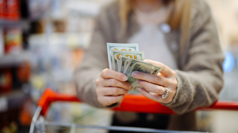 An individual wearing a big diamong ring on their hand holding four hundred dollar bills
