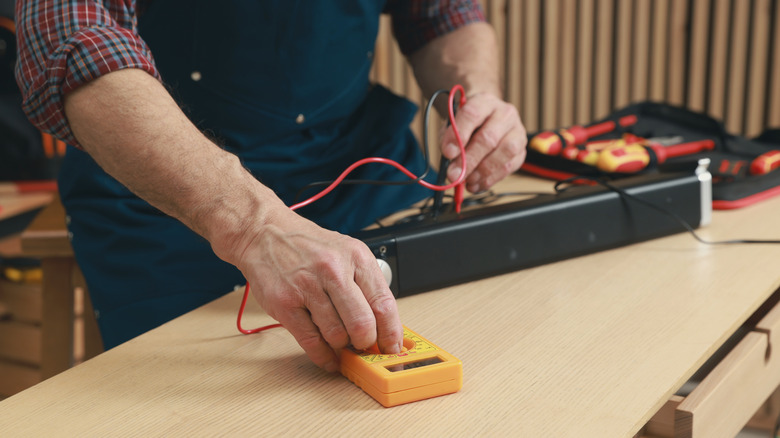 A person testing a soundbar's electrical signals.