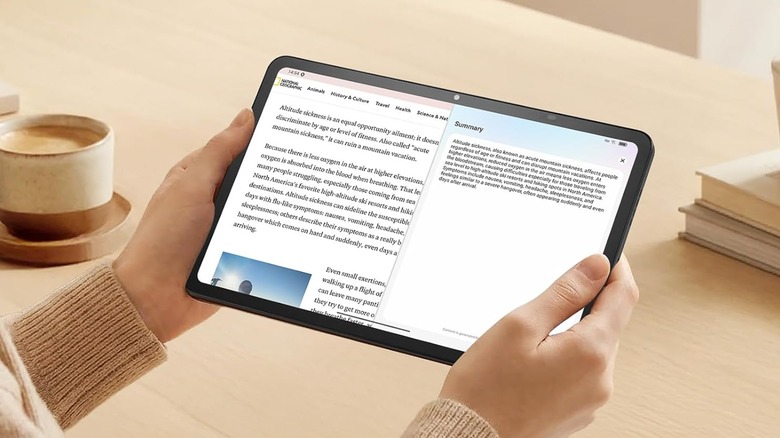 A closeup of a TCL Nxtpaper 11 Gen 2 as it is held in an individual's hands, a coffee cup can be seen