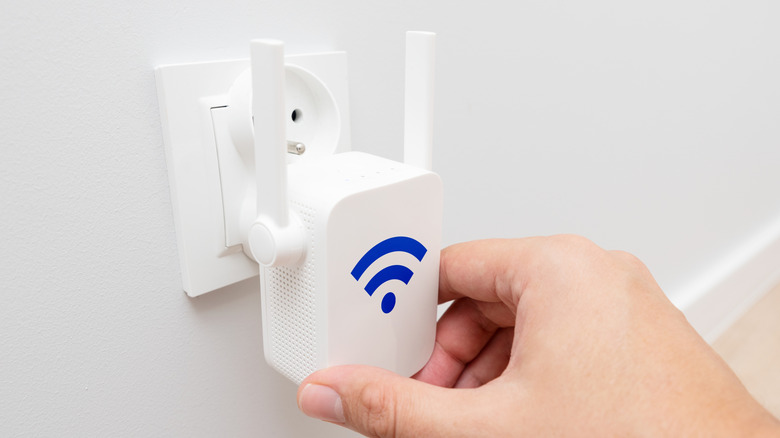 Person plugging a Wi-Fi extender to a wall outlet