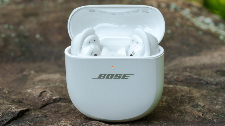 The Bose QuietComfort Ultra Earbuds (2nd Gen) placed on a rock in an outdoor setting.