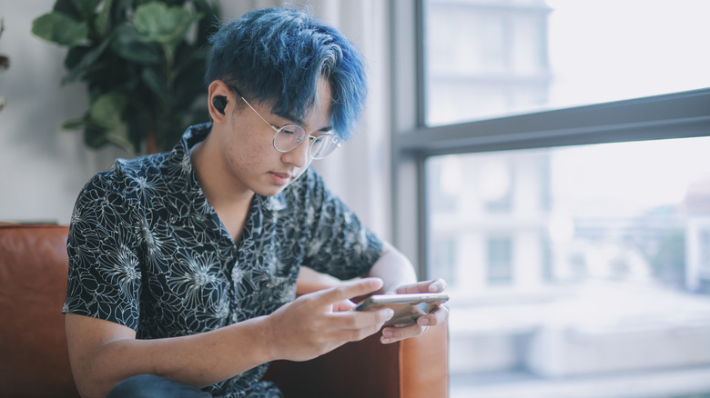 A man using his phone in landscape mode while sitting on the couch.