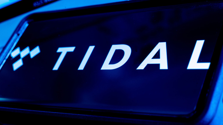 TIDAL logo displayed on a smartphone screen with blue lighting.