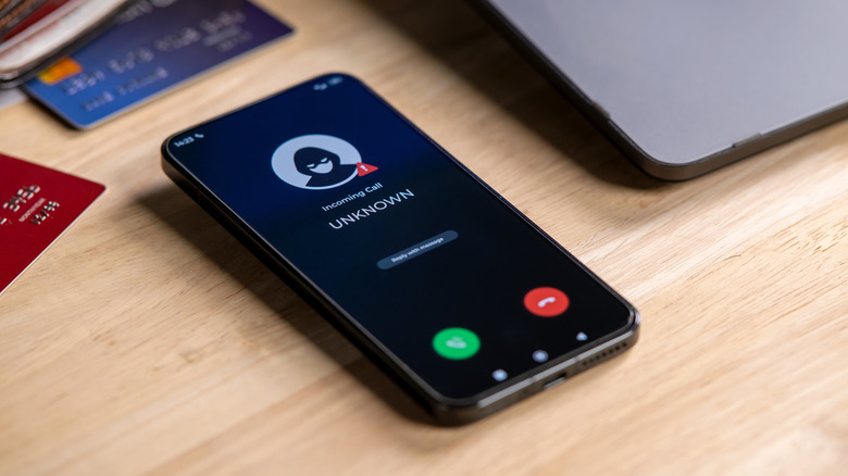 A phone lying on a table, receiving a call from an unknown number