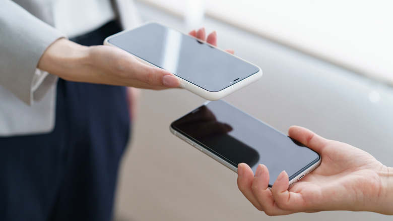 Two people holding their phones near each other to transfer files