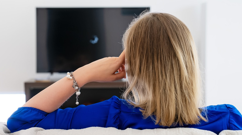 A blonde woman looking at a TV showing a loading screen