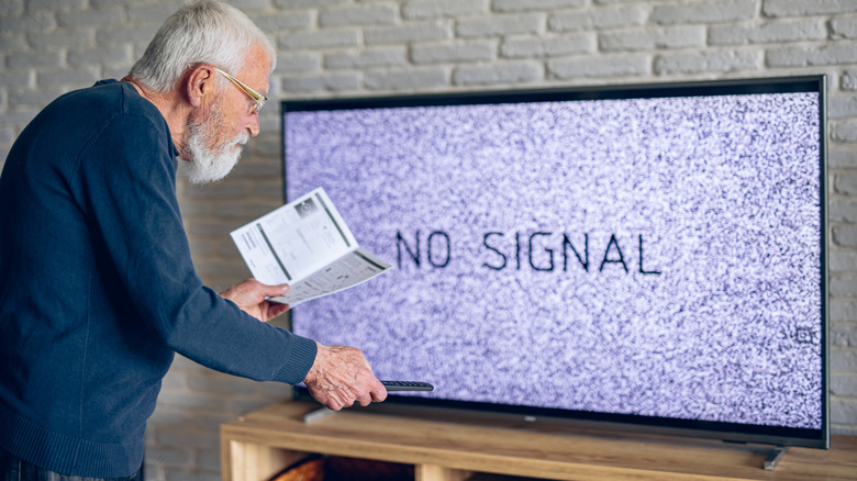 TV showing no signal with old man fixing it