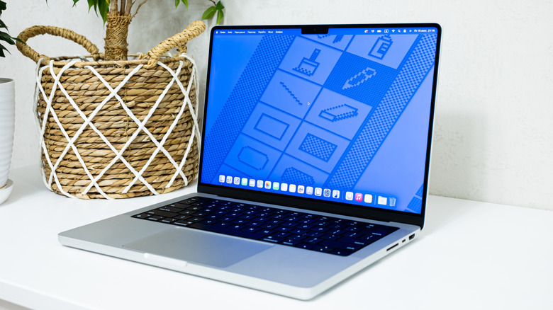A Silver MacBook displaying a blue background sitting on a white table