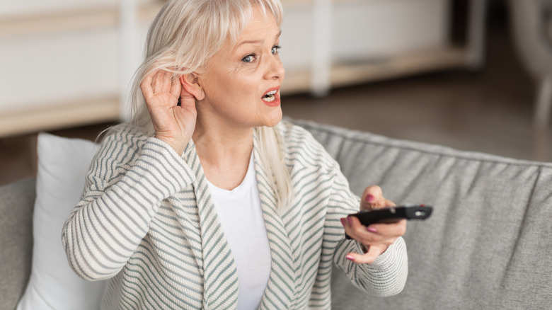 Older woman can't hear the TV while holding remote