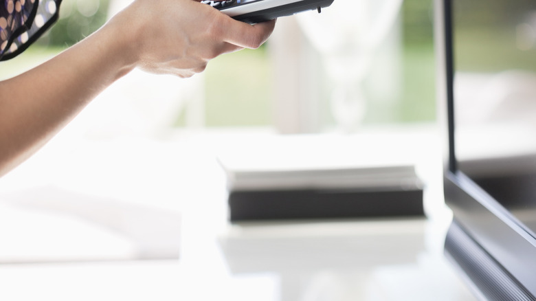 Woman using remote with TV while frowning