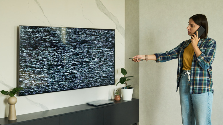 Woman using remote with pixelated TV