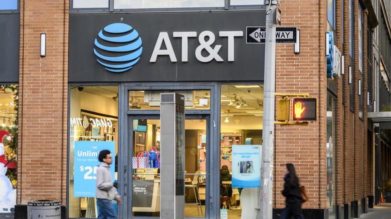 The entrance of an AT&T store in a city with pedestrians walking in front.